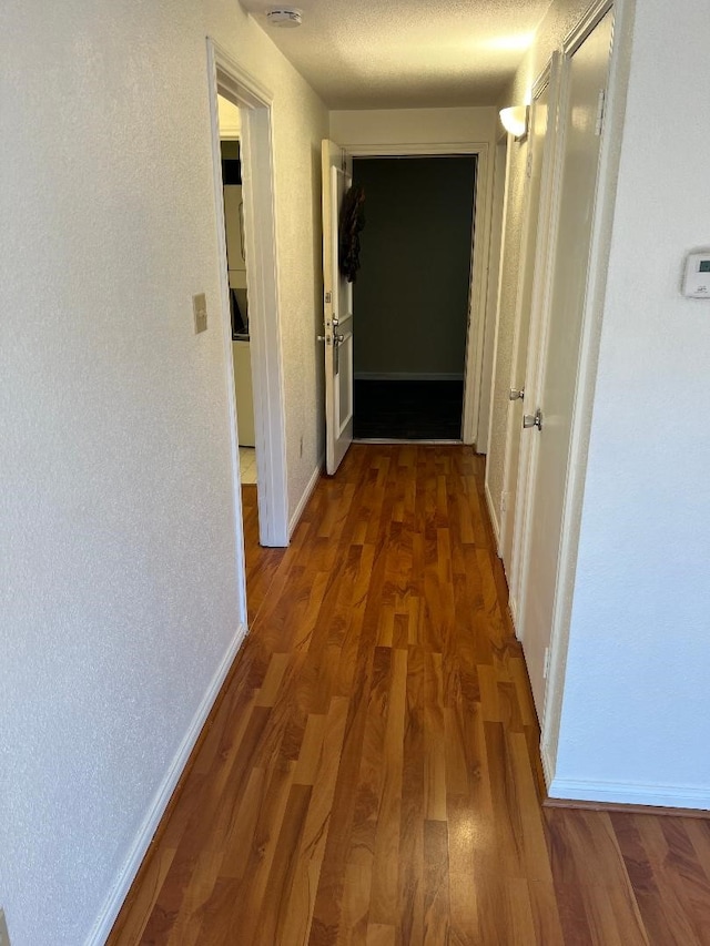 hallway with dark hardwood / wood-style floors and a textured ceiling