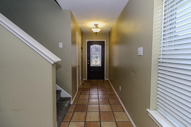 foyer entrance with dark tile patterned flooring and a healthy amount of sunlight