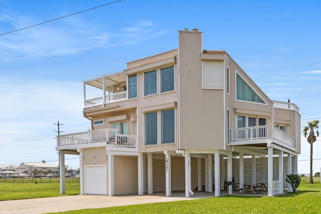 back of house featuring a garage, a lawn, and a balcony