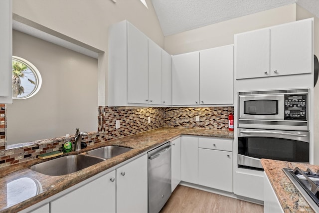 kitchen with sink, dark stone counters, white cabinetry, and appliances with stainless steel finishes