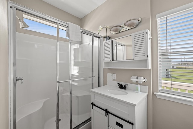 bathroom featuring a healthy amount of sunlight, walk in shower, and vanity