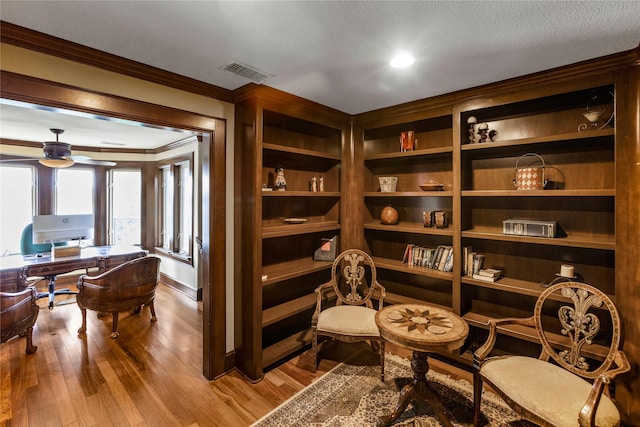 living area featuring hardwood / wood-style flooring, ornamental molding, and ceiling fan