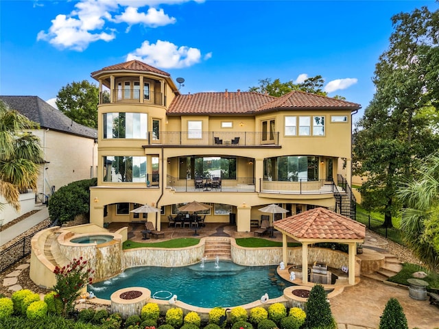 back of house with an in ground hot tub, a bar, pool water feature, a balcony, and a gazebo