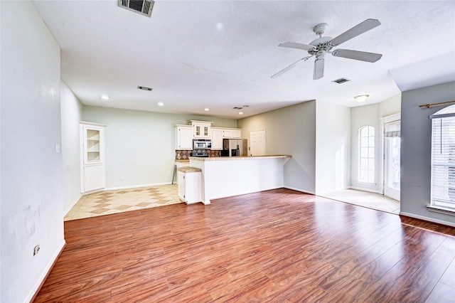 unfurnished living room with light wood-type flooring, a textured ceiling, and ceiling fan