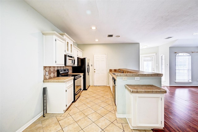 kitchen with white cabinets, stainless steel appliances, decorative backsplash, and tile countertops