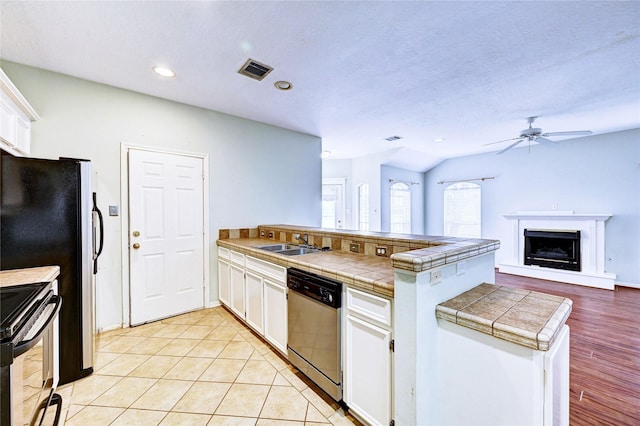 kitchen featuring kitchen peninsula, appliances with stainless steel finishes, sink, white cabinets, and tile counters