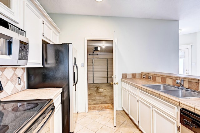 kitchen featuring sink, appliances with stainless steel finishes, white cabinetry, and tile counters