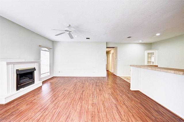 unfurnished living room with ceiling fan and light hardwood / wood-style flooring