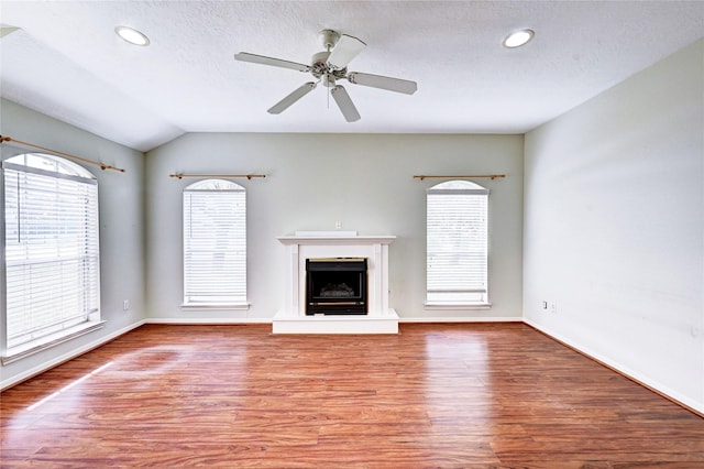 unfurnished living room featuring vaulted ceiling, ceiling fan, a textured ceiling, and wood-type flooring