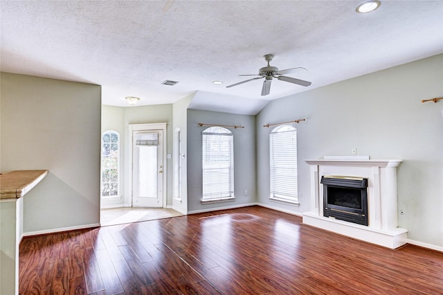 unfurnished living room featuring ceiling fan, hardwood / wood-style floors, a textured ceiling, and vaulted ceiling