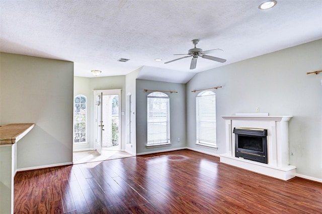 unfurnished living room with wood-type flooring, a textured ceiling, vaulted ceiling, and ceiling fan