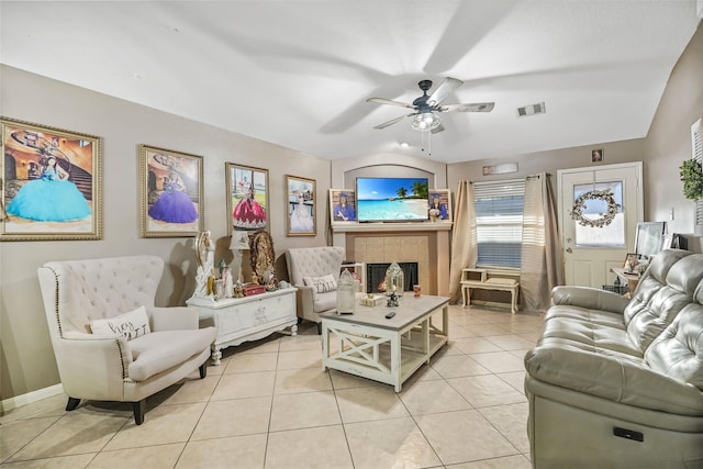 tiled living room with ceiling fan and a fireplace