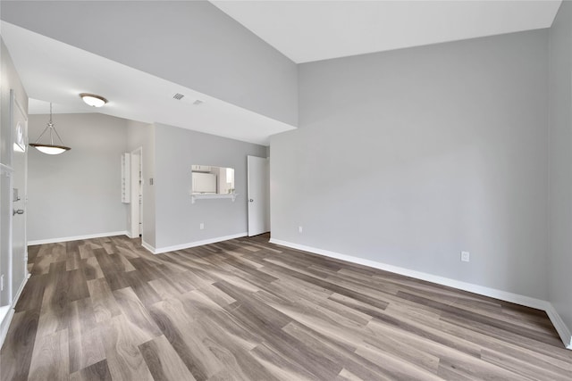 unfurnished living room featuring hardwood / wood-style floors and vaulted ceiling