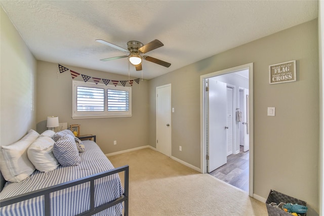 bedroom with ceiling fan, light carpet, and a textured ceiling