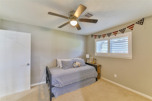 bedroom featuring light carpet, a textured ceiling, and ceiling fan