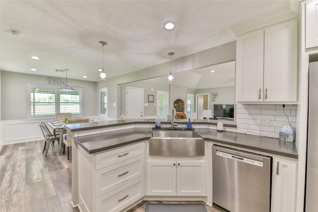 kitchen with stainless steel dishwasher, sink, hanging light fixtures, and white cabinets