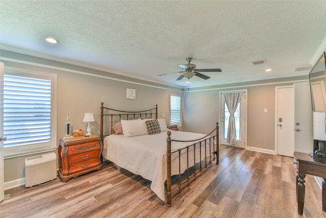 bedroom with hardwood / wood-style floors, crown molding, a textured ceiling, and ceiling fan