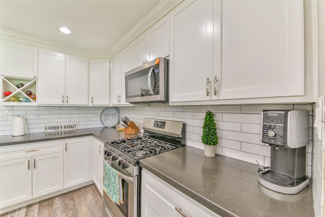 kitchen with appliances with stainless steel finishes, white cabinets, light hardwood / wood-style floors, and decorative backsplash