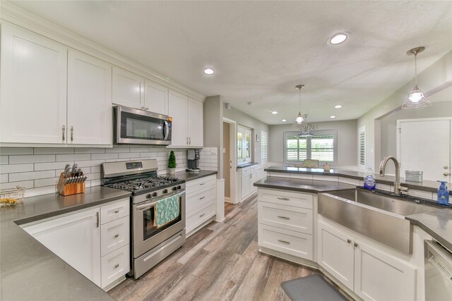 kitchen featuring hanging light fixtures, white cabinetry, appliances with stainless steel finishes, and sink