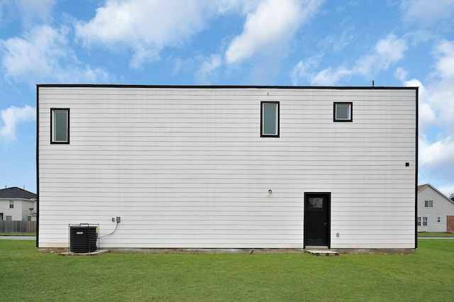 back of house featuring central AC unit and a lawn