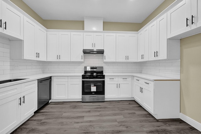 kitchen with hardwood / wood-style flooring, appliances with stainless steel finishes, backsplash, and white cabinets