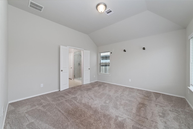 carpeted spare room featuring vaulted ceiling