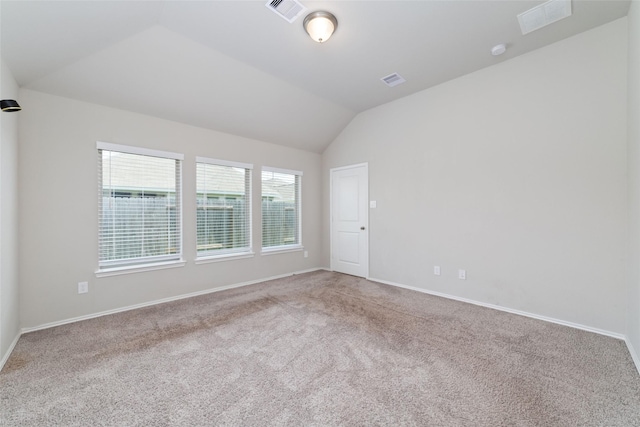 carpeted spare room with vaulted ceiling