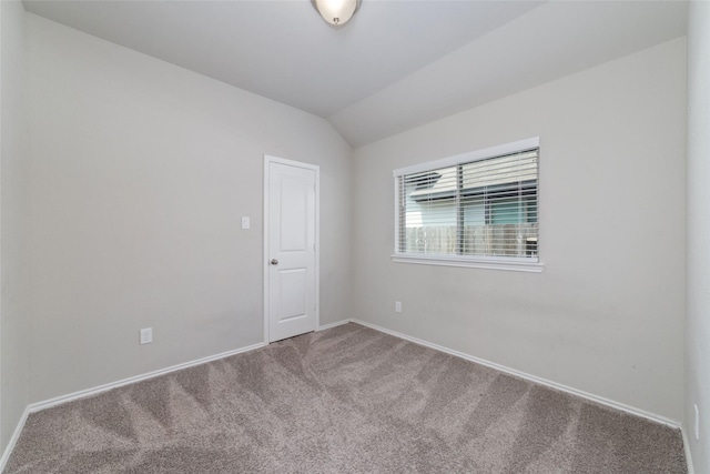 carpeted spare room featuring vaulted ceiling