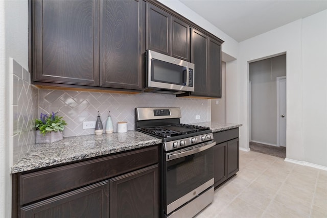 kitchen with dark brown cabinets, light stone countertops, appliances with stainless steel finishes, and tasteful backsplash