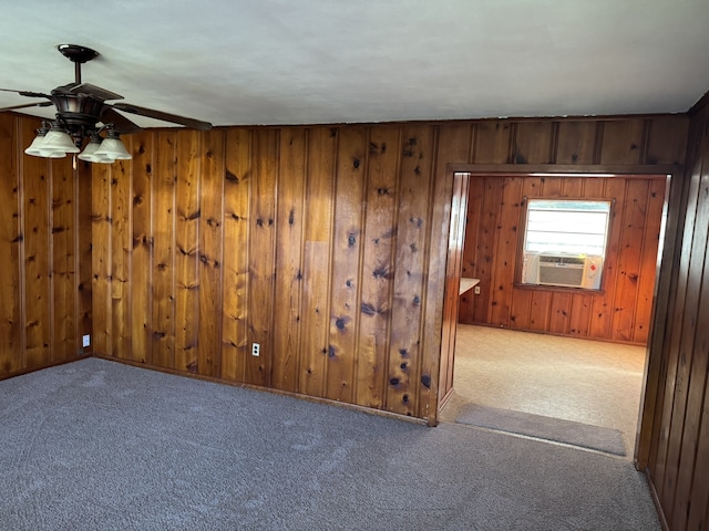 carpeted spare room featuring wooden walls, cooling unit, and ceiling fan