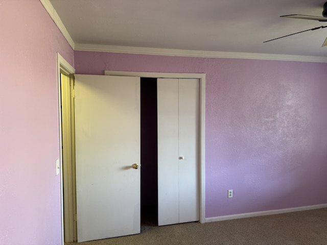 unfurnished bedroom with ceiling fan, a closet, ornamental molding, and carpet floors