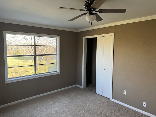 unfurnished bedroom with a closet, ceiling fan, carpet floors, and multiple windows