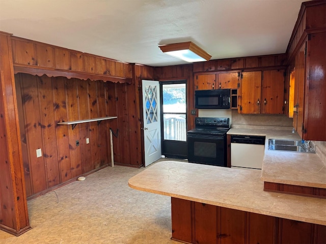 kitchen with black appliances, wood walls, kitchen peninsula, and sink