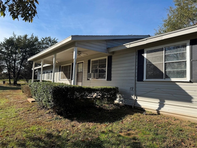 view of side of home featuring ceiling fan and a yard