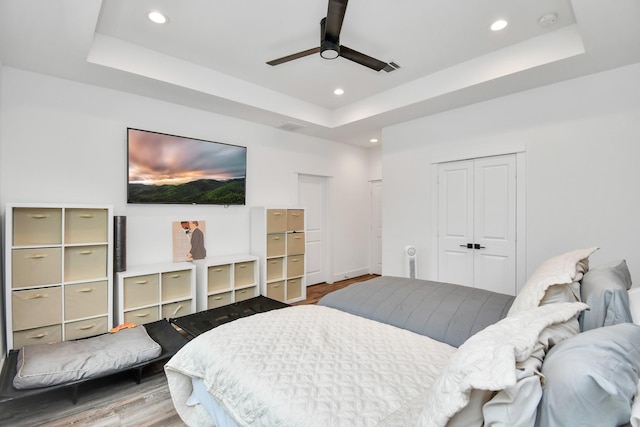 bedroom with ceiling fan, a closet, and a tray ceiling