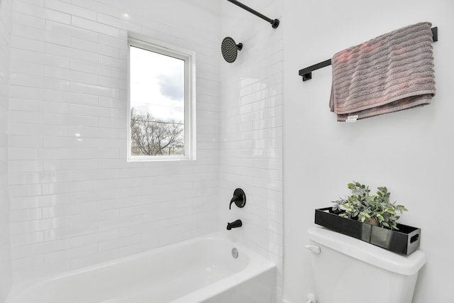 bathroom with toilet and tiled shower / bath