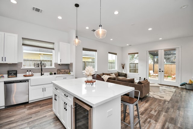 kitchen featuring pendant lighting, white cabinets, beverage cooler, and stainless steel dishwasher