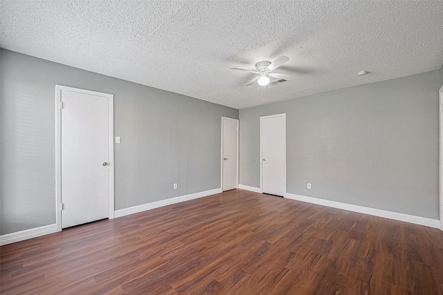 empty room with ceiling fan, dark wood-type flooring, and a textured ceiling