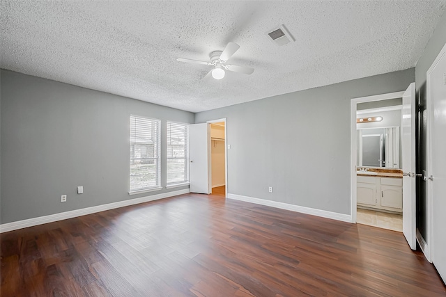 unfurnished bedroom with ceiling fan, ensuite bathroom, hardwood / wood-style floors, and a textured ceiling