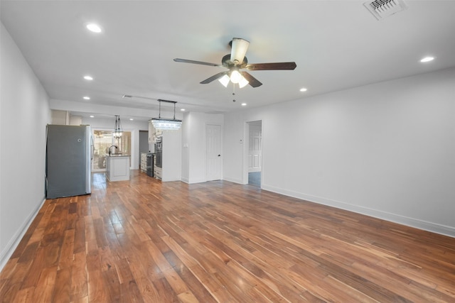 unfurnished living room featuring sink, hardwood / wood-style floors, and ceiling fan