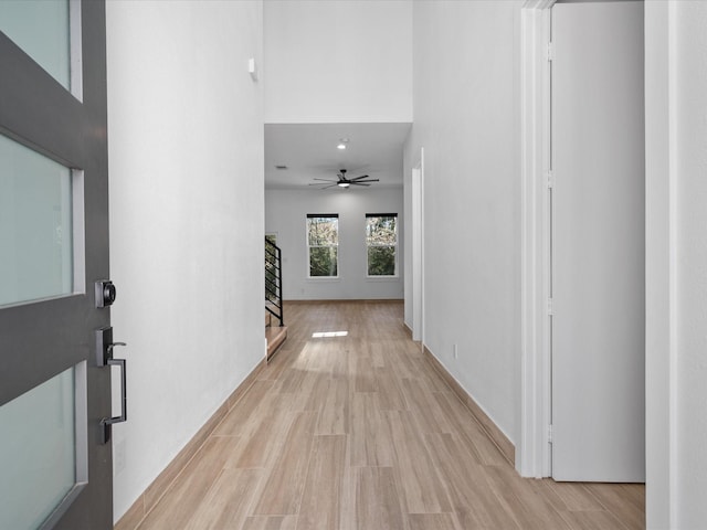 hall featuring light hardwood / wood-style flooring and a high ceiling