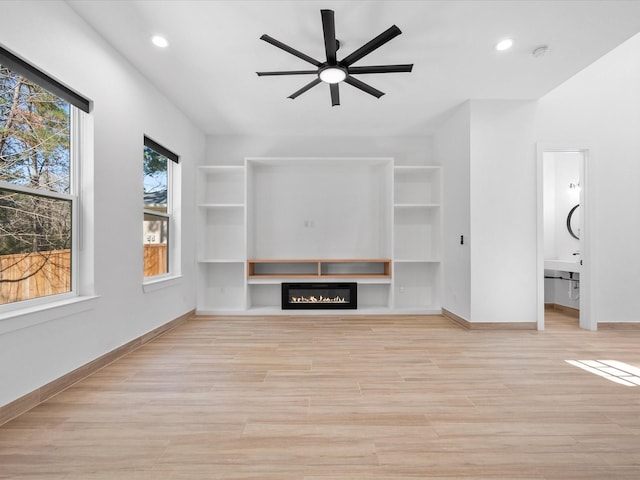 unfurnished living room with light hardwood / wood-style floors, built in shelves, and ceiling fan