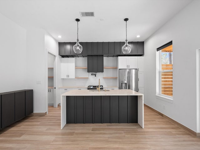 kitchen featuring white cabinets, pendant lighting, stainless steel fridge, and sink