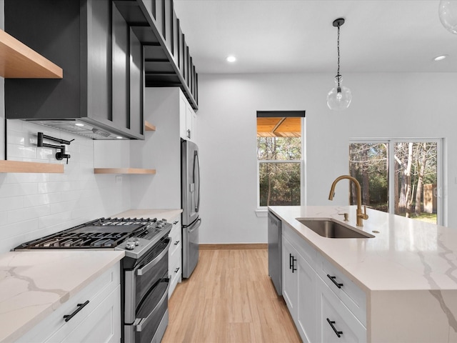 kitchen with light stone counters, sink, white cabinets, and stainless steel appliances