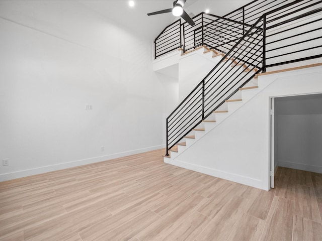 stairway featuring ceiling fan, high vaulted ceiling, and hardwood / wood-style floors