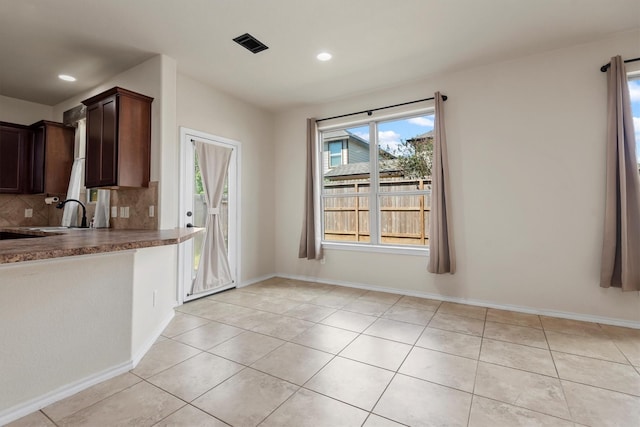 kitchen with decorative backsplash, light tile patterned floors, dark brown cabinetry, and sink