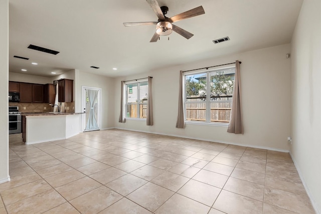 unfurnished living room featuring ceiling fan, sink, and light tile patterned floors