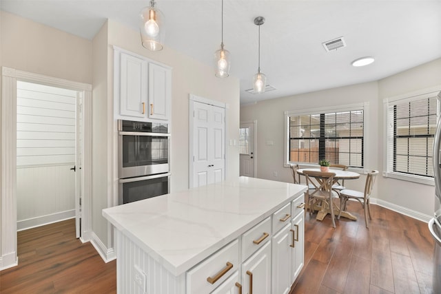 kitchen featuring pendant lighting, dark wood-type flooring, white cabinetry, a center island, and stainless steel double oven