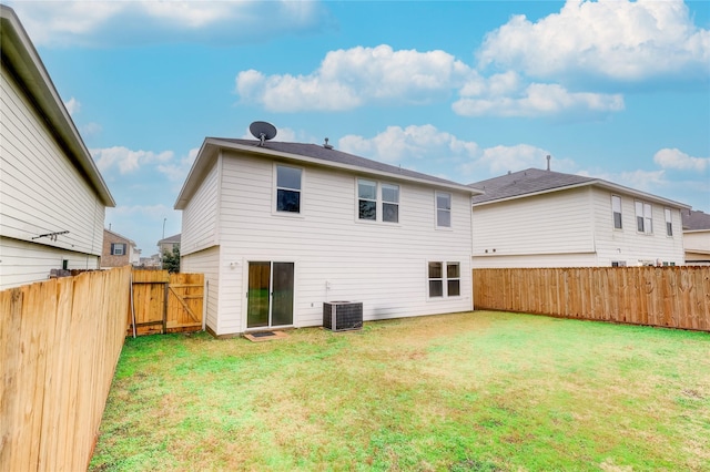 rear view of house with central AC unit and a yard