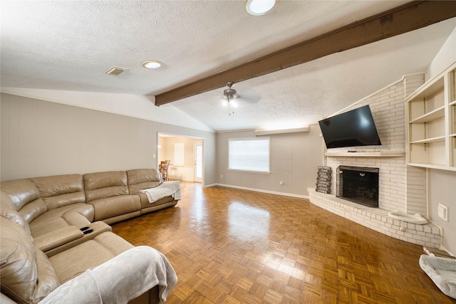 living room featuring ceiling fan, lofted ceiling with beams, a brick fireplace, a textured ceiling, and parquet floors